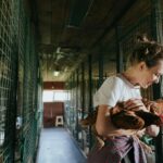 A beginner chicken keeper holding a fluffy Buff Orpington hen in a small suburban backyard with a compact chicken coop and run visible behind them